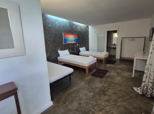 Quarto triplo no Hotel PZero em Albufeira com três camas individuais, parede de destaque escura, TV e comodidades modernas