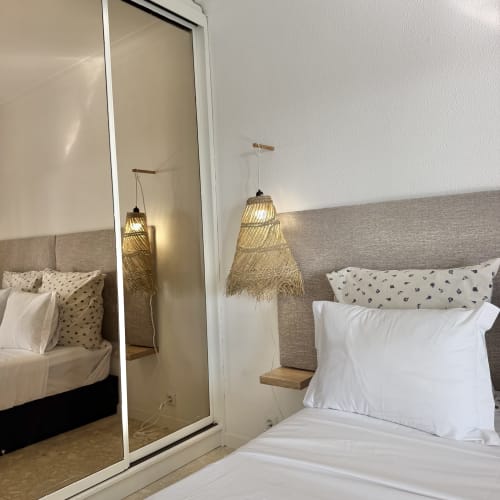Quarto moderno com cabeceira cinza, almofadas brancas, luminárias trançadas e espelho na República do Sul, Charneca da Caparica