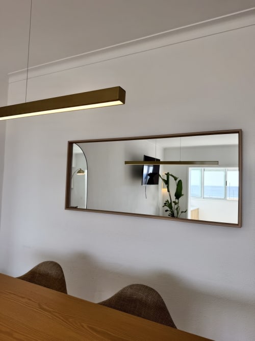 Interior moderno do apartamento em República do Sul com mesa de madeira, espelho com moldura marrom e vista para a costa pelas janelas