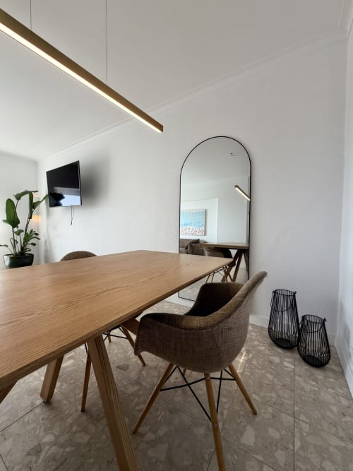 Área de refeições moderna no apartamento SEA 9 da República do Sul com mesa de madeira, cadeiras trançadas e espelho arqueado em Aroeira,