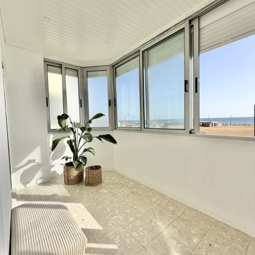 Varanda ensolarada e luminosa com vista para o mar, plantas em vasos e paisagem costeira em Charneca da Caparica, Portugal