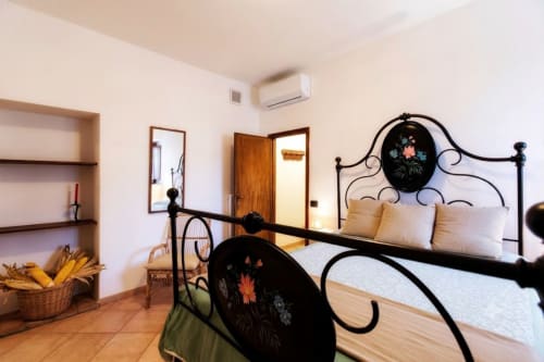Camera elegante all'I Castagnini B&B di Montecatini Val di Cecina con letto in ferro battuto ornato, biancheria crema e decori floreali
