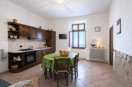 Zona cucina-sala da pranzo rustica dell'Appartamento Arancio presso I Castagnini B&B, Montecatini Val di Cecina, con mobili in legno e