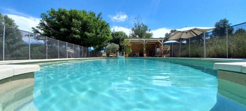 Kristallklares Schwimmbecken im Domaine Bellavigne Gîtes et Spa in Forcalquier mit Liegestühlen und Sonnenschirmen