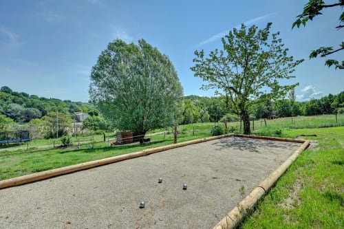 Boccia-Spielplatz des Domaine Bellavigne Gîtes et Spa in Forcalquier, umgeben von üppigen Gärten und Bäumen