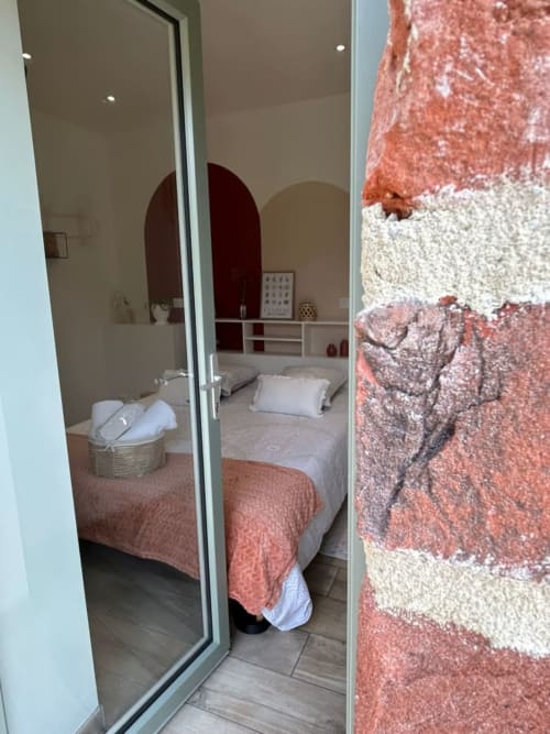 Chambre à La Cour d'Hortense B&B à Sailly-Flibeaucourt avec lit, miroir bombé et vue sur le jardin par porte vitrée