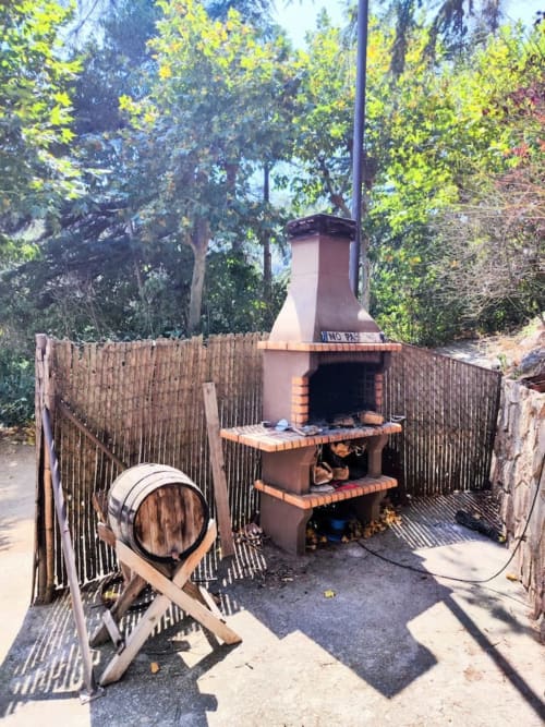 Barbacoa exterior con barril de madera en la casita L'Amagatall de Cal Tonedor en Vallgorguina, Barcelona