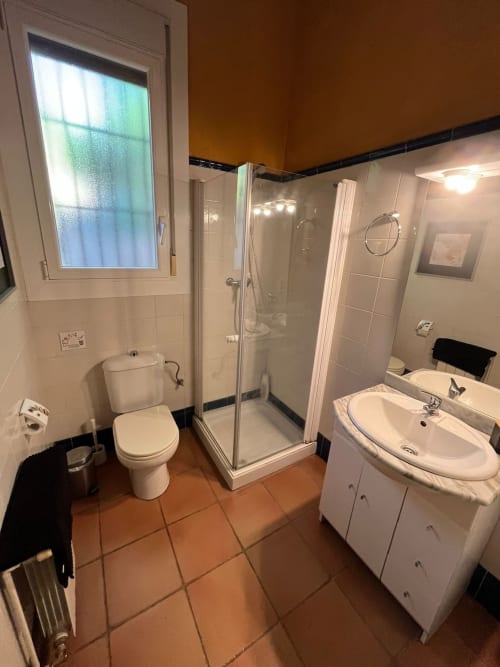 Baño moderno con ducha, inodoro y lavabo en la casa rural L'Amagatall de Vallgorguina, Barcelona