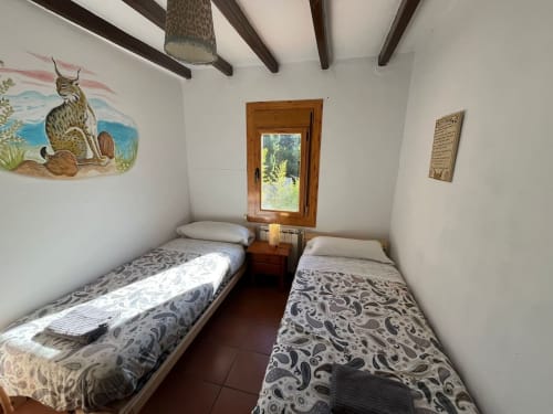 Acogedora habitación doble en la casa rural NIU HOUSE de L'Amagatall de Cal Tonedor, Vallgorguina, con vigas rústicas y vistas a la montaña