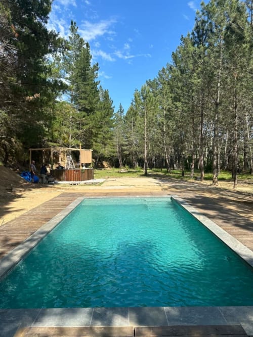 Piscina turquesa rodeada de altos pinos en la casa rural L'Amagatall de Cal Tonedor en Vallgorguina, Barcelona
