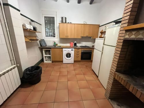 Cocina rústica de L'Amagatall de Cal Tonedor en Vallgorguina con muebles de madera, azulejos de barro, chimenea y