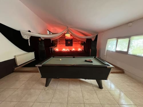 Sala de juegos con mesa de billar e iluminación ambiental roja en la casa rural NIU HOUSE en Vallgorguina, Barcelona