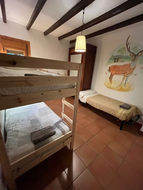 Dormitorio rústico con literas, vigas de madera y arte de ciervos en la casa rural Vallgorguina, Barcelona