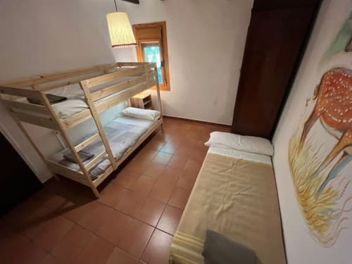 Dormitorio con cama litera de madera y cama individual en la casita L'Amagatall, Vallgorguina Barcelona