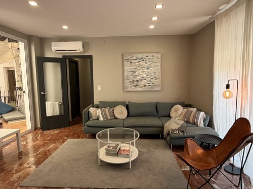 Modern living room in The Ruzafa Market Apartment, València, with grey sofa, coffee table, and brown leather chair