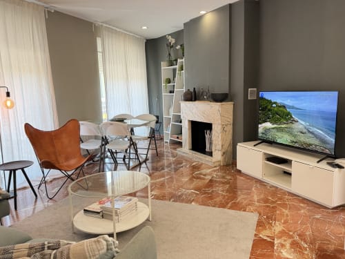 Modern living room in The Ruzafa Market Apartment, València, with TV, fireplace, marble flooring, and city views.