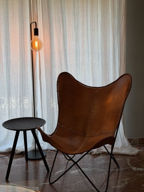 Cognac leather butterfly chair with studs beside black side table under warm pendant light, The Ruzafa Market Apartment