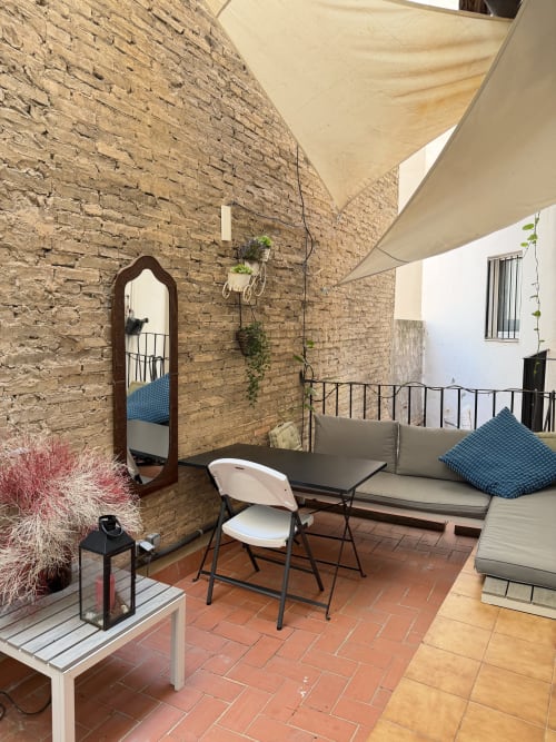 Stylish Valencia apartment terrace with brick wall, seating area, dining table, mirror, and shade sail at Stay Gest Ruzafa