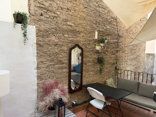Ruzafa Market Apartment terrace in València with brick walls, seating area, mirror, and potted plants under shade sail