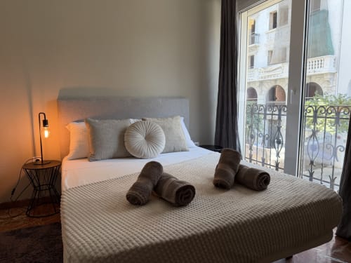 Bright bedroom at Ruzafa Market Apartment in Valencia with city view, double bed, rolled towels, and modern furnishings
