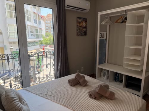 Bright bedroom in The Ruzafa Market Apartment, València, with city view balcony, white wardrobe, and towels on bed