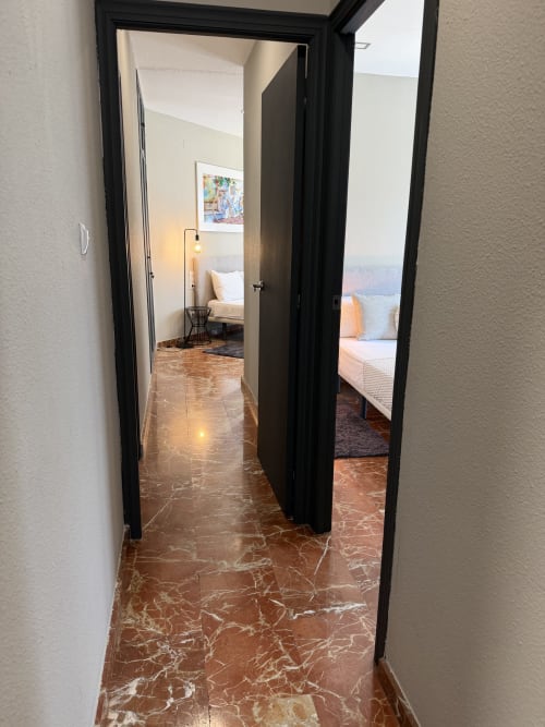 Black-framed doors opening to bedroom in The Ruzafa Market Apartment, Valencia, with marble floors and city views