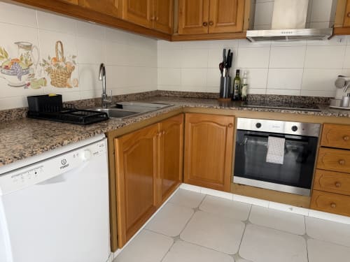 Modern kitchen in Ruzafa Market Apartment, València with wooden cabinets, granite countertop, stainless steel appliances and