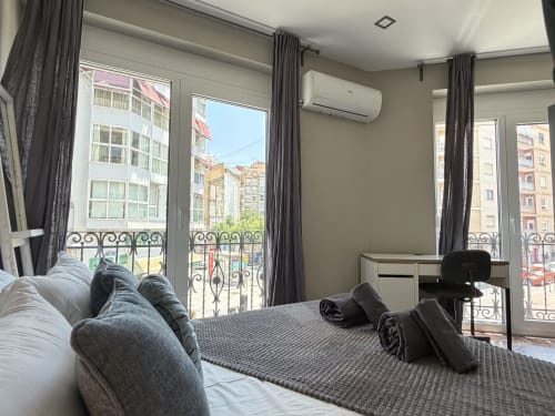 Modern bedroom with city views in The Ruzafa Market Apartment, València, featuring balconies overlooking urban architecture
