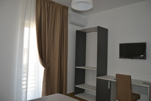 Camera moderna al Makasa B&B di Villapiana con scaffali neri, TV a schermo piatto, scrivania e vista giardino
