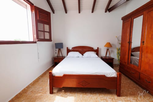 Chambre Anthurium à Otantik Caribbean à Saint-Louis avec lit en bois, draps blancs, penderie et vue sur la ville