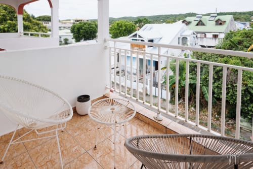 Authentique balcon caribéen avec vue sur la ville, chaises tressées et collines de Saint-Louis en arrière-plan
