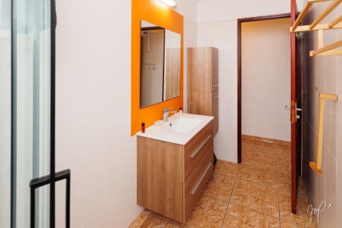 Salle de bains moderne de l'appartement Anthurium à l'hôtel Otantik Caribbean, Saint-Louis, avec miroir à cadre orange et meuble-lavabo en bois