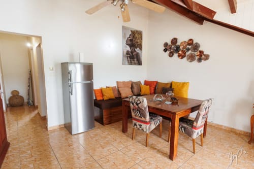 Salle à manger moderne à Otantik Caribbean avec table en bois, sièges confortables aux couleurs vives et cuisine en acier inoxydable
