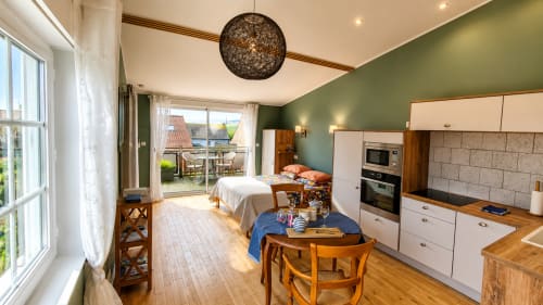 Studio au Ô de Mer à Sangatte avec cuisine, lit, coin repas, mur d'accent vert et vue jardin par la terrasse