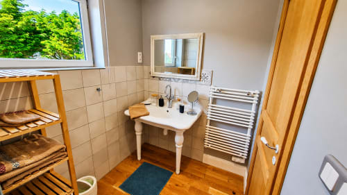 Salle de bain moderne du studio Ô de Mer, Sangatte, avec lavabo sur colonne, sèche-serviettes chauffant, miroir et meubles en bois