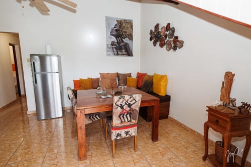 Appartement caribéen authentique à Saint-Louis avec table à manger en bois, coussins colorés et décoration d'inspiration africaine