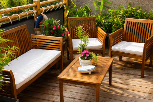 Chaises longues en bois avec coussins blancs sur la terrasse d'Ô de Mer à Sangatte, vue sur le jardin fleuri