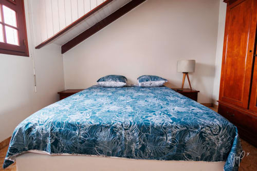 Chambre moderne avec literie bleue à motifs à l'hôtel Otantik Caribbean à Saint-Louis, poutres en bois et porte en bois