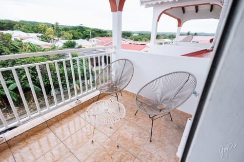 Balcon de l'appartement Baliser à Otantik Caribbean, Saint Louis, avec deux chaises et vue sur la ville et les collines luxuriantes