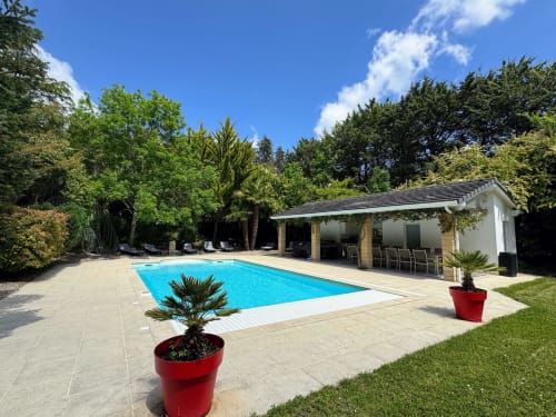 Luxury pool area at Domaine de Bize in Mirepoix, France with modern pavilion and lush gardens