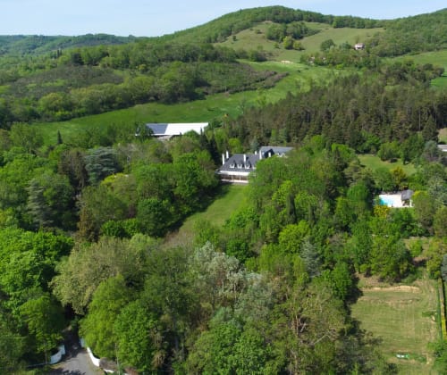 Aerial view of Domaine de Bize manor surrounded by forests and rolling hills in Mirepoix, Ariège