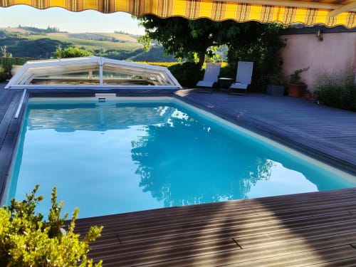 Beauregard B&B's heated pool with retractable cover, wooden deck, loungers, and panoramic vineyard views near Donneville,