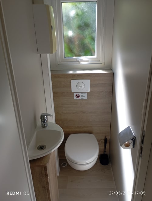 Salle de bain moderne du mobilhome Le Clocher De Neyran avec fenêtre, lavabo et toilettes à Saint Gervais sur Mare