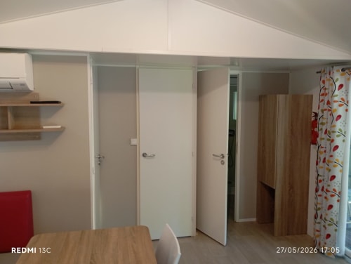 Intérieur du mobil-home au Clocher De Neyran avec portes blanches, mobilier en bois et vue sur le jardin