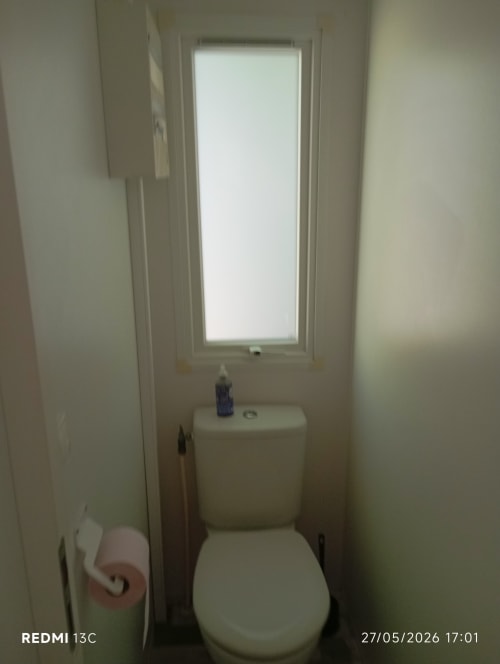Toilettes blanches dans une petite salle de bain avec fenêtre au mobil-home Le Clocher De Neyran, Saint Gervais sur Mare