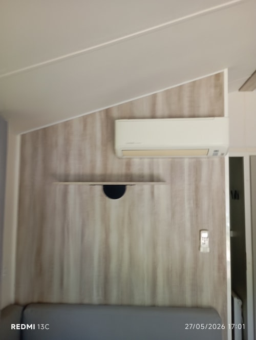Chambre moderne du mobil-home Le Clocher De Neyran avec climatiseur mural et boiseries clair