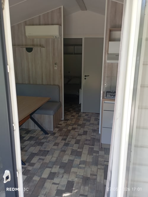Intérieur du mobilhome au Clocher De Neyran avec coin repas, kitchenette et chambre à Saint Gervais sur Mare