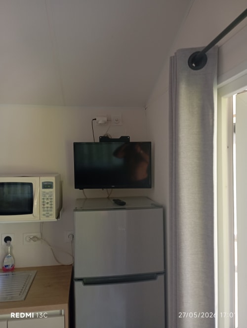 Coin chambre du mobilhome avec TV murale, micro-ondes et réfrigérateur au Clocher De Neyran