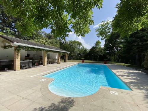Piscina de resort con terraza de piedra, casa de piscina y jardines manicurados en Domaine de Bize en Mirepoix, Ariège
