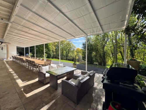 Patio cubierto en Domaine de Bize con mesa de comedor, área de estar, parrilla y vistas al bosque en Mirepoix